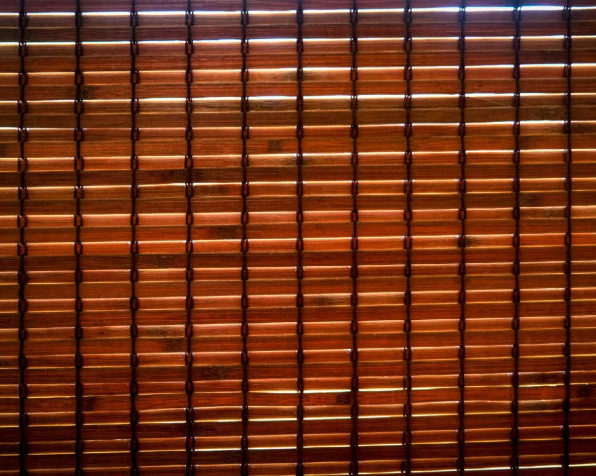 Close-up of a woven bamboo roller blind with warm light filtering through